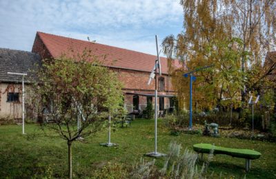 Kunsttour Betzin-Brunne - Die Skulpturen im Garten und Werkstatt im Hintergrund